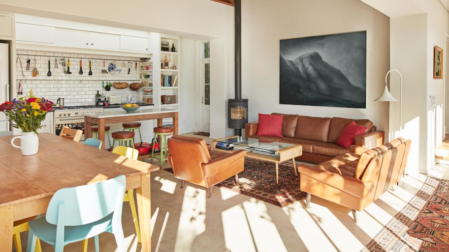 An open plan kitchen and a living room with leather sofas